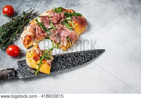 Italian Pizza With Parma Ham, Arugula And Cheeseon A Kitchen Table. White Background. Top View. Copy