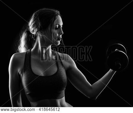 Slim Athletic Woman Holding Dumbbell In The Hand On Black