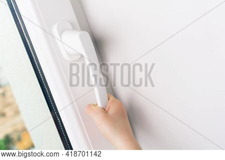 Child Hand Trying To Open A Window Handle Of A Closed White Window - Prevent Child Hazard Concept