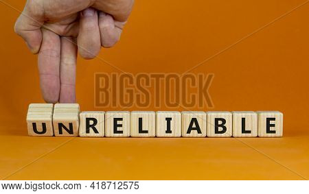 Unreliable Or Reliable Symbol. Businessman Turns Wooden Cubes And Changes The Word Unreliable To Rel