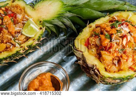 Thai Cashew Chicken Fried Rice Served In A Pineapple Bowl With Sriracha And Peanut Satay Sauce