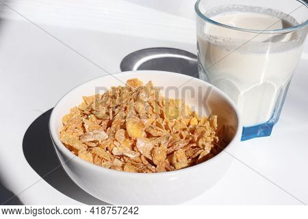 Bowl Of Cereal And Glass Of Milk On White Background. Healthy Breakfast With Cornflakes And Milk. To