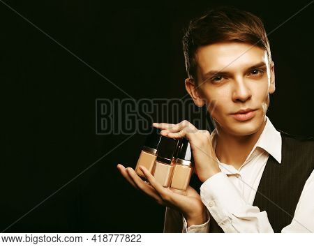 Young male make up artist posing with foundation for make-up