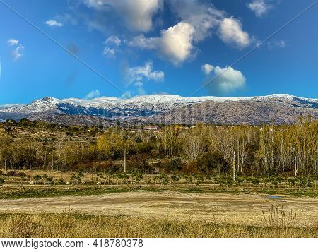 Photo With Copy Space Of Snow-capped Mountains With A Village And Fields In The Foot