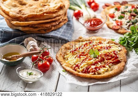Traditional Hungarian Crusty Langos Served With Grated Cheese, Ketchup, Sausages, Dips, Ketchup And 