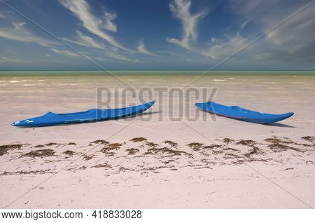 Two Kaiaks On A Deserted Tropical Beach On Holbox Island In Mexico. In The Background The Caribbean 