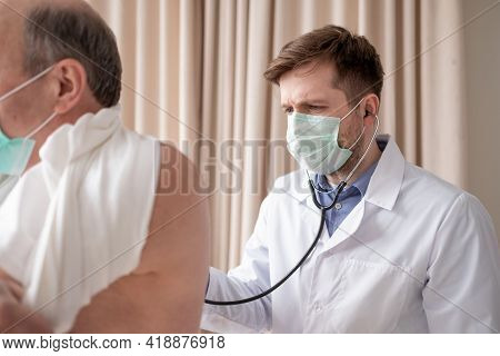 Caucaian Male Doctor Listening To A Senior Males Breathing With A Stethoscope