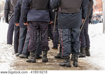 Russian Police Officers Legs In Black Ankle Boots, Red Stripe Pants And With Rubber Tonfa Night Stic