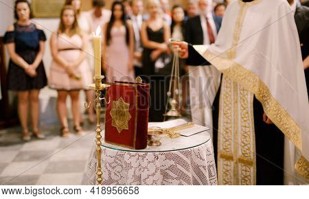 Wedding Ceremony In An Orthodox Church. The Priest In A White Cassock Stand In The Church At The Alt