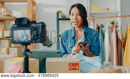 Young Asia Lady Fashion Designer Using Mobile Phone Receiving Purchase Order And Show Clothes Record