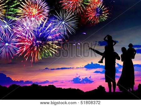 Parents with two children watching fireworks at sunset