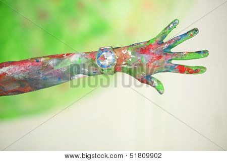 Hand with wristwatch with open palm covered in paint 