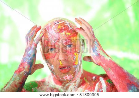 Whole painted bald man with a surprised face holding his head 