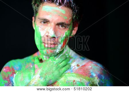 Portrait of a man with hand on neck covered in paint in the studio