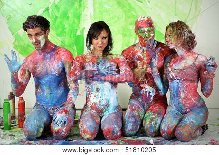 Four people sitting on the floor in studio with whole body in the paint and make hand gestures