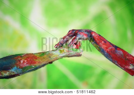 Female hand covered in paint holds male hand in a fist