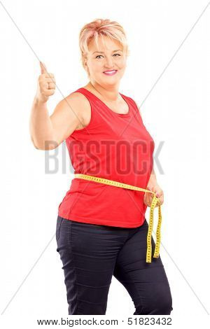 Happy mature woman measuring her waist after diet and giving thumb up, isolated on white background