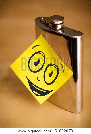 Drawn smiley face on a post-it note sticked on a hip flask