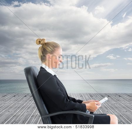 Composite image of businesswoman sitting on swivel chair with tablet on base before ocean