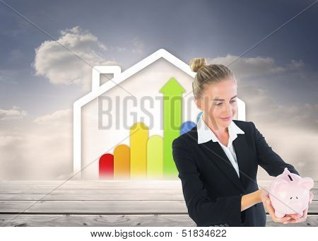 Composite image of blonde businesswoman holding piggy bank in front of house containing statistic