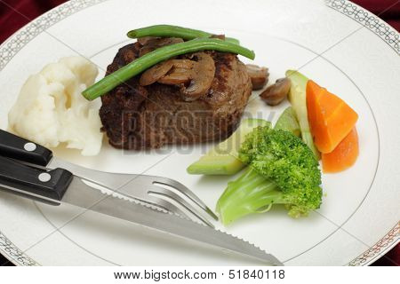 Beef tournedos (tenderloin fillet steak) served with mushrooms, steamed beans, courgettes, cauliflower, carrot and broccoli, a minimalist modern take on a traditional favourite.