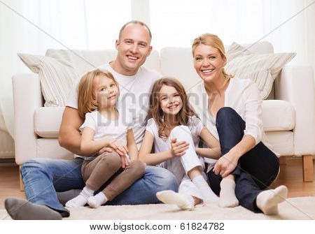 family, children and home concept - smiling family with and two little girls sitting on floor at home