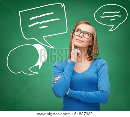 happiness and people concept - happy smiling young woman in black eyeglasses dreaming with taxt bubbles on blackboard