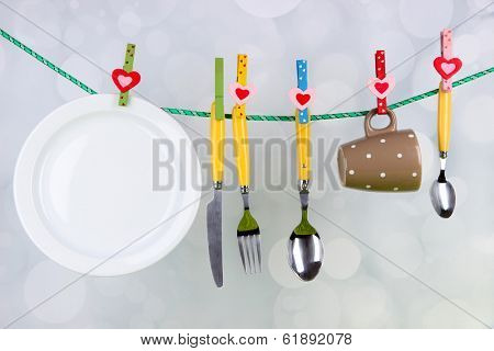 Tableware dried on rope on bright background