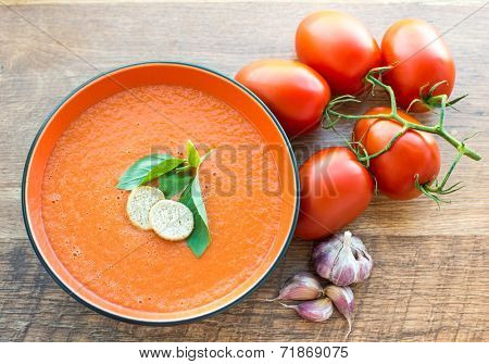 A bowl of tomato soup gaspacho with basil and crackers