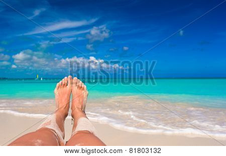 Female feet on white sandy beach