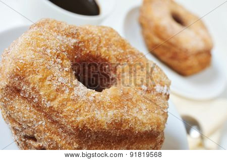 some croissant-doughnut pastries sprinkled with sugar and a cup of coffee