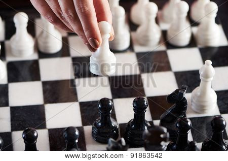 Hand With White Pawn Over Chessboard