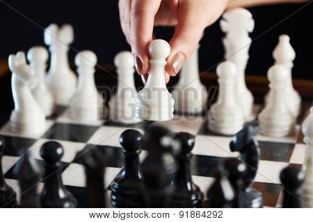 Hand With White Pawn Over Chessboard