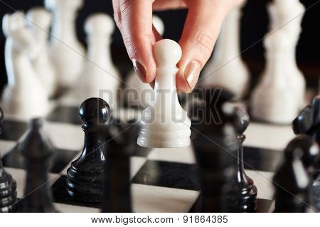 Hand With White Pawn Over Chessboard