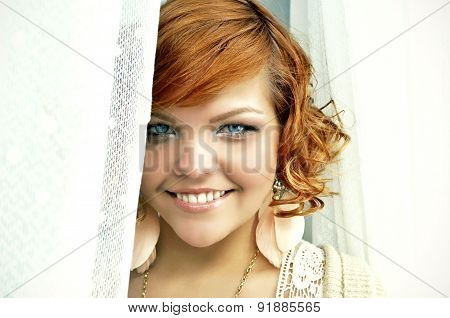 Stylish happy young woman with short curly red hair and bright blue eyes.