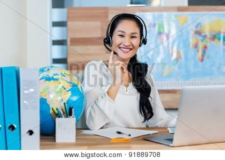 Pretty travel agent smiling at camera in the office