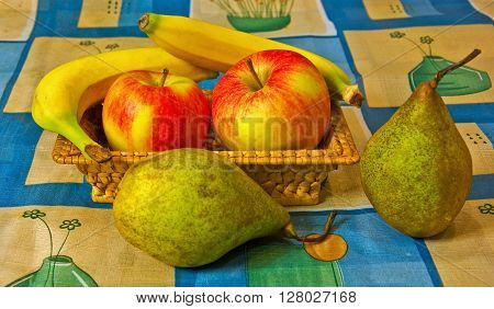 Apples pears and bananas in a basket on the dining table
