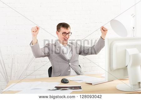 Winner businessman happy, succesful, in white modern office interior, sitting at computer table. Office worker in eye glasses, job in internet. High key, soft tone. Businessman win prize, gambling.