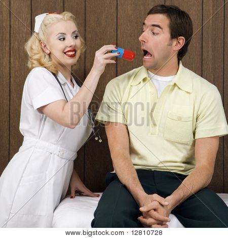 Caucasian mid-adult female nurse  giving mid-adult man giant pill.