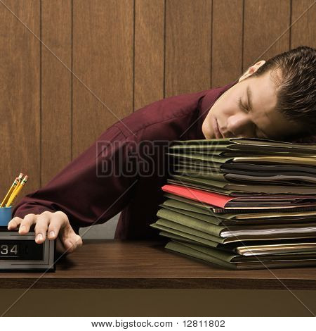 Lüneburg Mid retro Kaufmann sitzen am Schreibtisch mit Kopf nach unten schlafen auf einem hohen Stapel von fol
