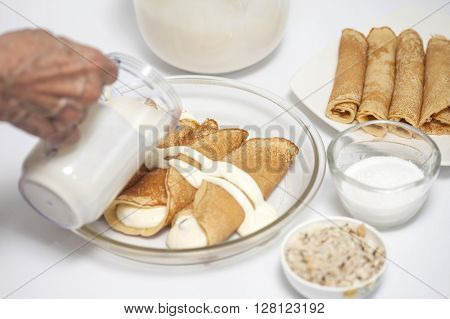 Adding sauce to the crepes to prepare topfen füllen