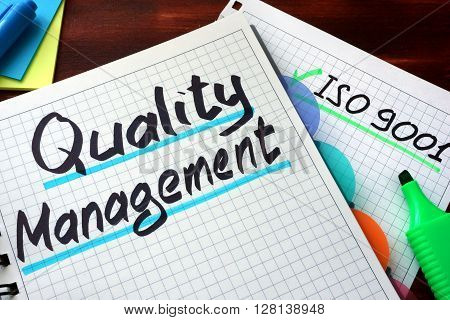 Quality Management System QMS written on a notepad with marker.