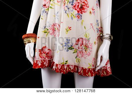 Sarafan with bracelets and watch. Wrist accessories on white mannequin. Bright bracelets on black background. Female clothing with stylish print.