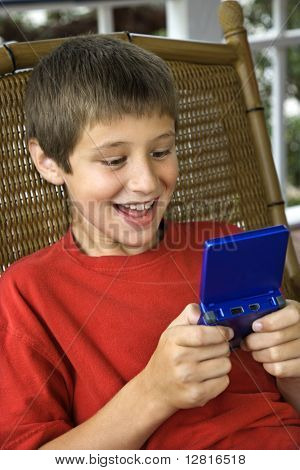 Kaukasische pre-teen jongen handheld video spel en glimlachen.