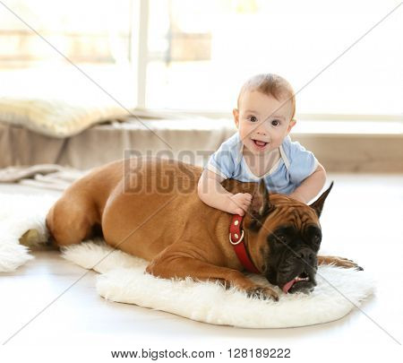 Little baby boy with boxer dog resting on the floor at home