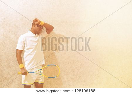 Squash player holding racket and touching his forehead after competition on squash court. Black man. Spotsman.