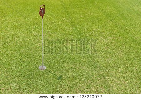Soft focus of a hole at putting cup hold showing number one pin at outdoor practice putting green, sunny day