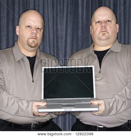 Caucasiano careca gêmeo homens segurando um computador portátil e olhar viewer.