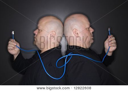 Caucasiano careca meados homens adultos gêmeos idênticos permanente voltar para trás segurando o cabo de ethernet.
