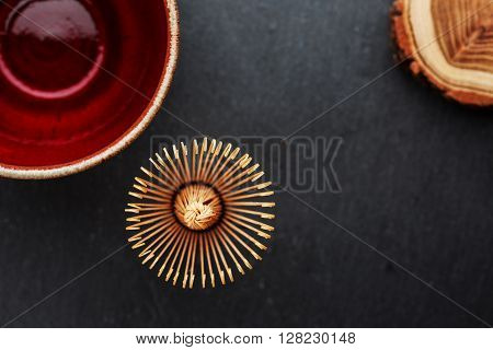 Ceramics bowl and chasen - special bamboo matcha tea whisk, lying on black stone background